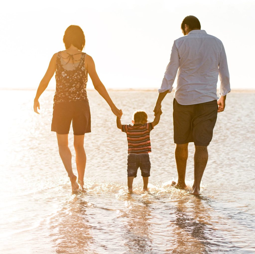 Beautiful family holding hands walking on the beach - My Safe Space 4 All